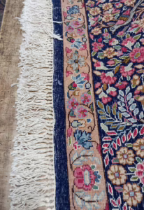 Teppichrand mit lockeren Fransen und aufgeribbeltem Gewebe vor dem maschinellen Ketteln